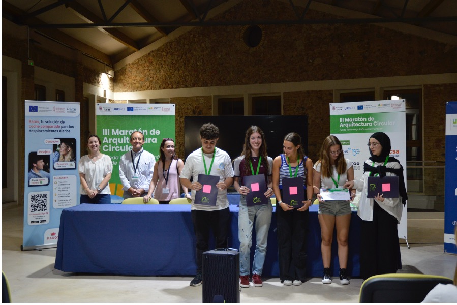 A group of people standing and holding awards in front of a table on stage. 