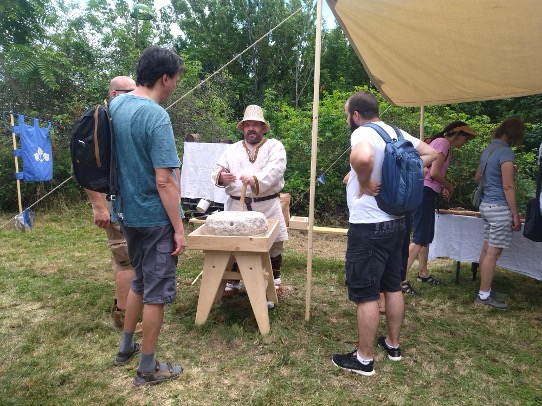 People watching a presentation of a person dressed as an ancient artisan.