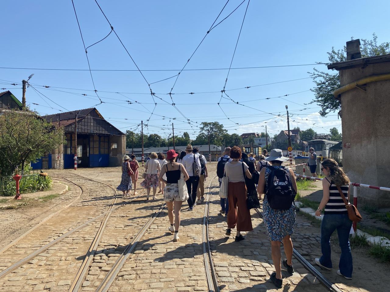 A group of people walking through a tram depot