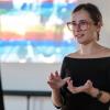 Portrait of Iris Popescu while giving a speech at a workshop. In the background there is part of the visual support.