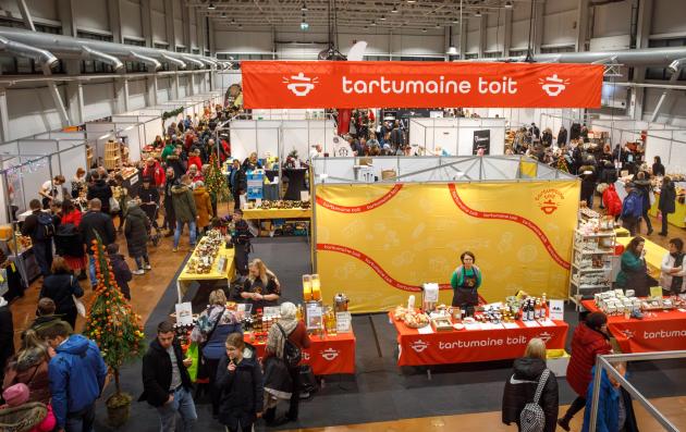 This image depicts a bustling indoor market or fair, likely focused on food and local products.