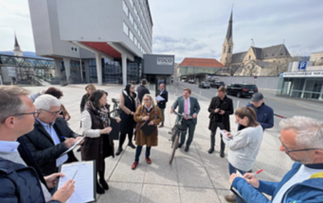 A group of people gathered outdoors in what appears to be an urban setting. 