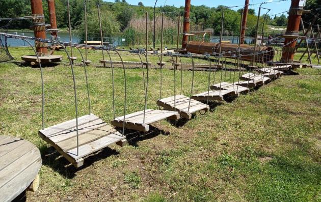 The picture shows a path with wooden playground equipment in a park