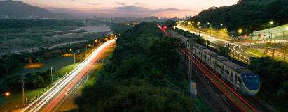 A road next to a train that crosses the tracks.