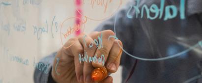 Person writing with a permanent marker on a transparent blackboard